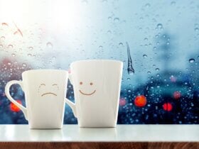 Dwa kubki z narysowanymi emocjami smutku i uśmiechu