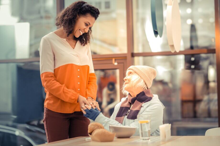 Młoda kobieta pomagająca starszej kobiecie poprzez zakup ciepłego posiłku