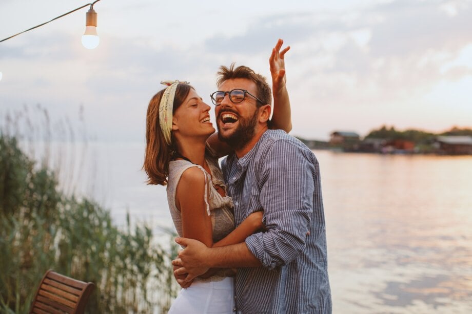 Young couple in love flirting by the river at sunset