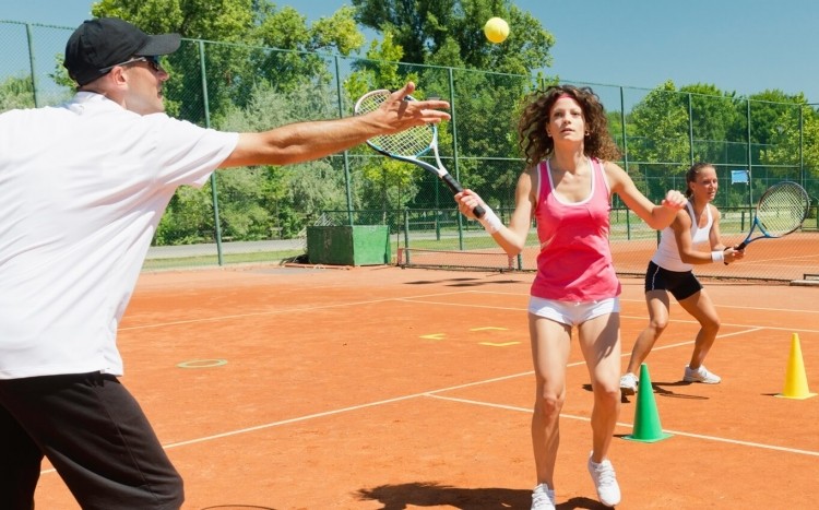 instruktor uczy dziewczyny grać w tenisa