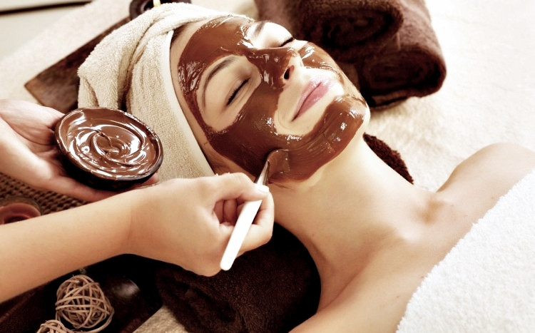 kosmetyczka nakłada płynną czekoladę na twarz kobiety